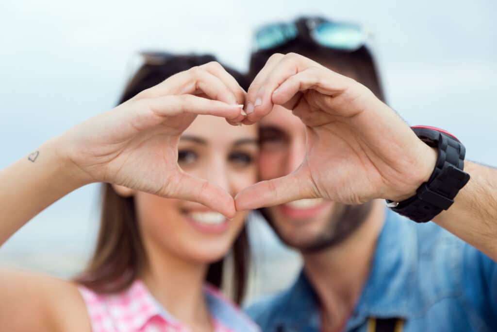 Un couple amoureux formant un coeur avec leurs mains