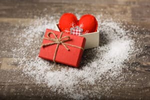 un coeur rouge dans une boîte rouge posée sur une table en bois saupoudrée de sel